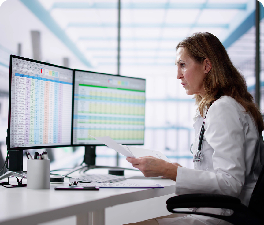 Doctor analyzing data on dual monitors.